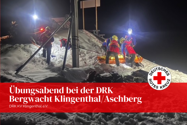 Dunkelheit, vom Flutlicht beleuchtet wird der Abschnitt in dem die Rettungsübung an der Schanze stattfindet. Drei Kameraden der Bergwacht sind im tiefen Schnee zu sehen.